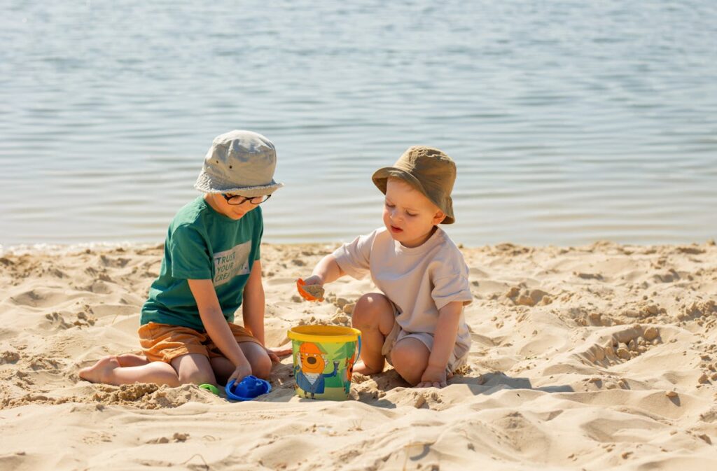 Children making a sandcastle while a nanny in Greece supervises on a Greek beach
